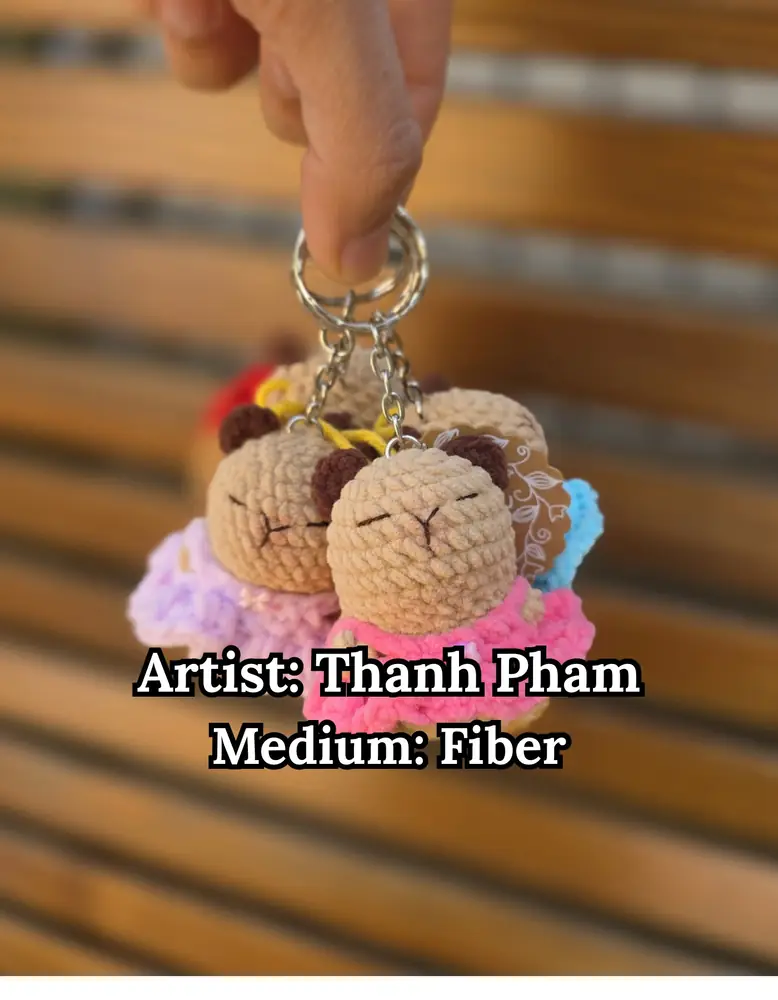 Crocheted capybara keychains in ruffled dresses, by Thanh Pham