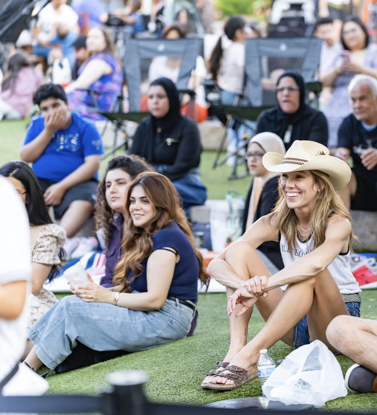 Festival-goers smiling on the lawn as they watch a performance