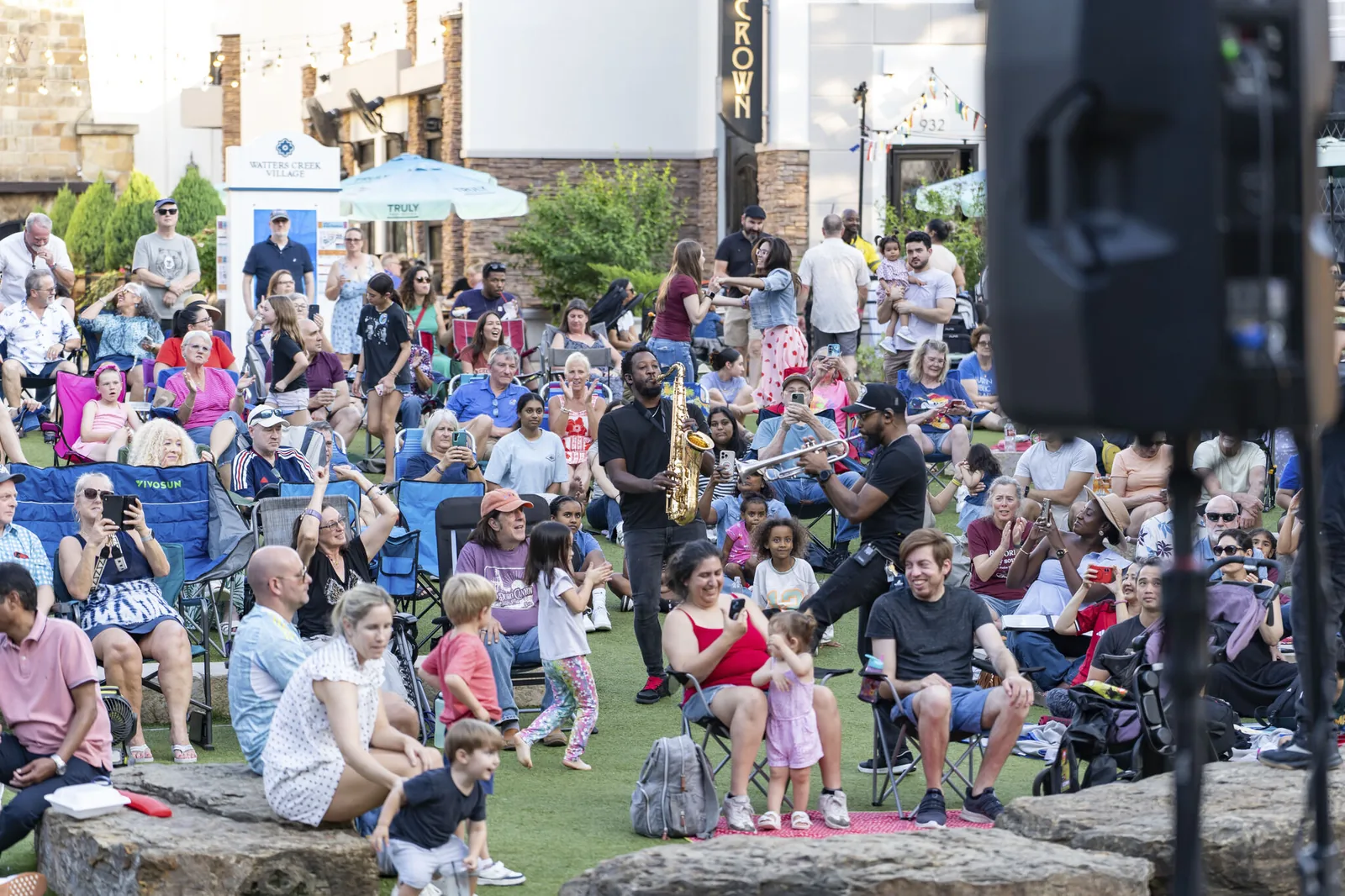 Saxophone and trumpet players perform in the middle of the festival crowd on the lawn