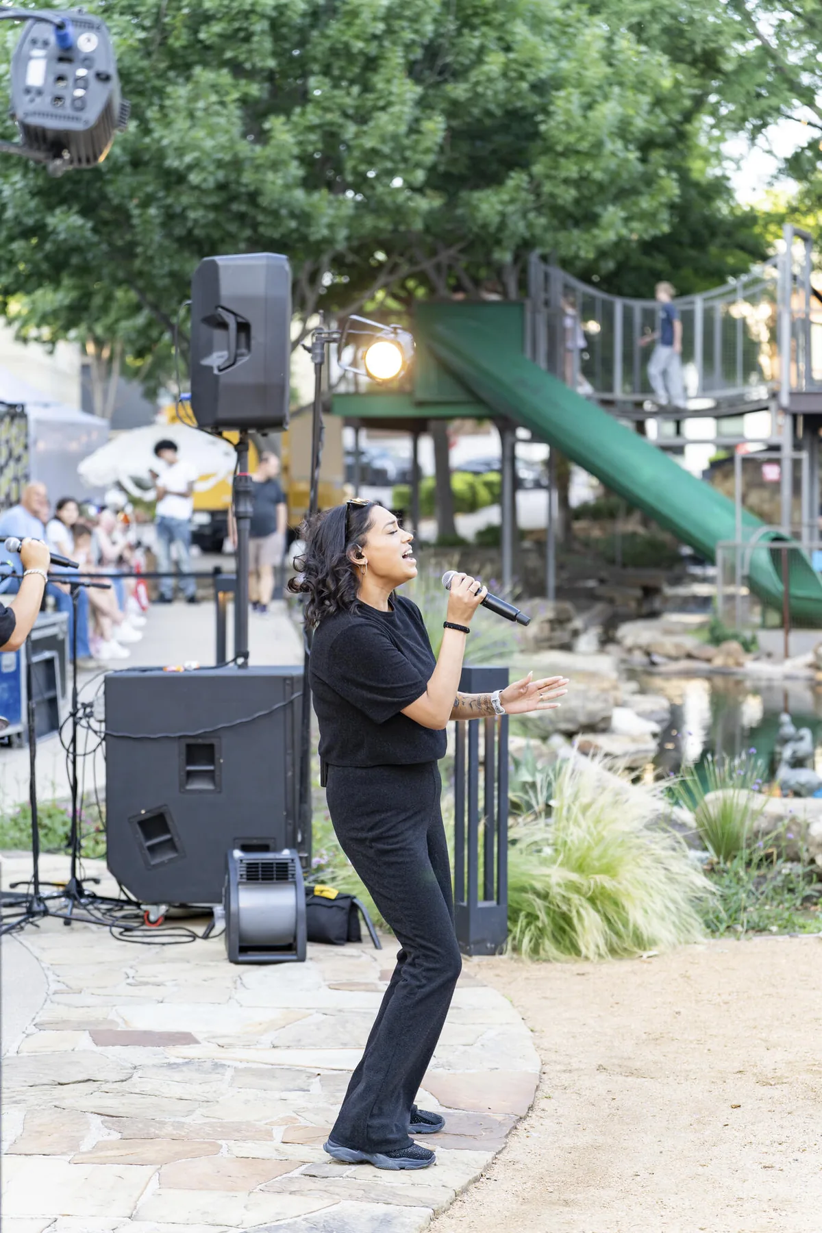 A vocalist sings into a microphone beside the festival stage at Watters Creek