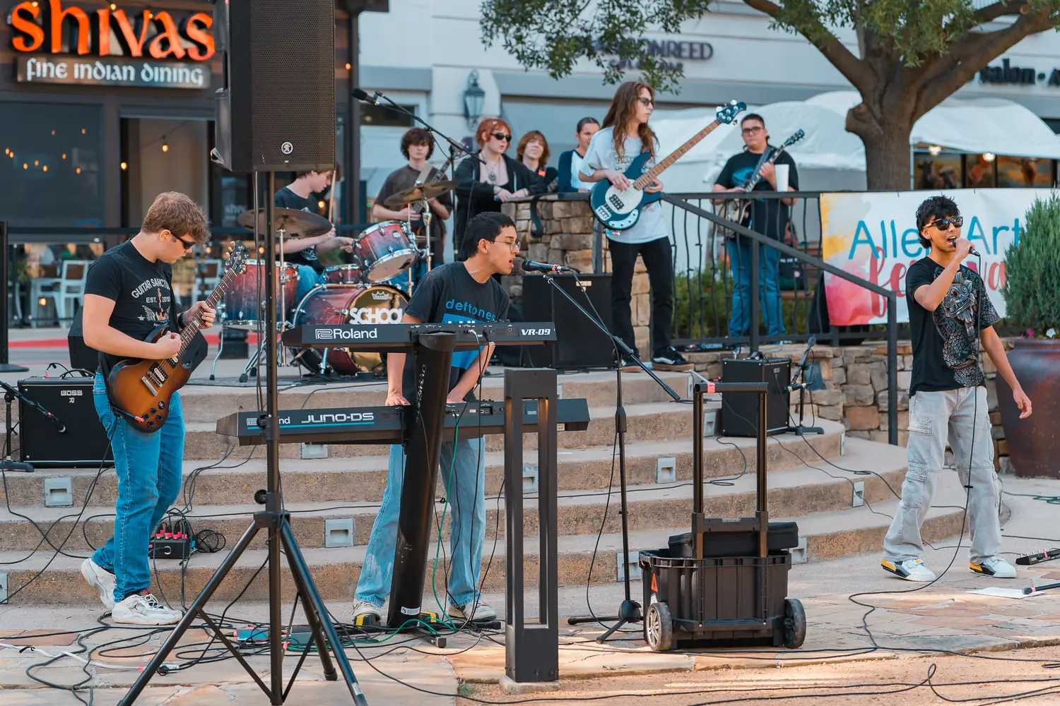 A youth band performs on the festival steps in front of an Allen Arts Festival banner